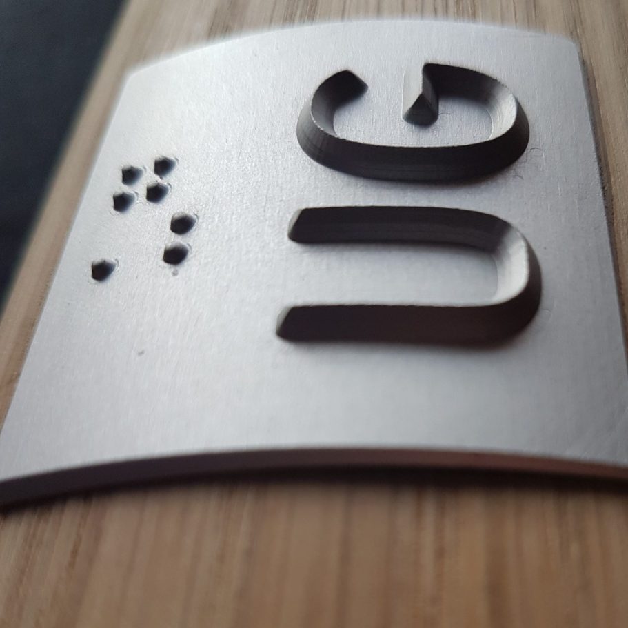 Schild mit taktilen Ziffern in Brailleschrift und Zahlen.